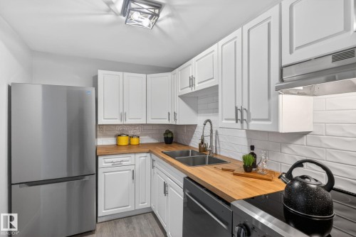 Kitchen featuring white cabinetry, wood-finish countertops, subway tile backsplash, and stainless steel appliances - 13332 106 Street, Edmonton, AB - Indoor Photo Showing Kitchen With Double Sink
