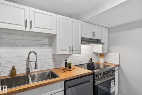 Kitchen featuring wood-finish countertops, white shaker-style cabinetry, and a white subway tile backsplash - 13332 106 Street, Edmonton, AB - Indoor Photo Showing Kitchen With Double Sink With Upgraded Kitchen