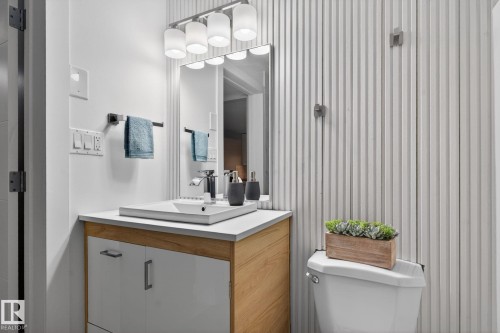 Bathroom featuring a floating wood-finish vanity with white drawer fronts, a rectangular vessel sink, and a multi-bulb vanity light - 13332 106 Street, Edmonton, AB - Indoor Photo Showing Bathroom