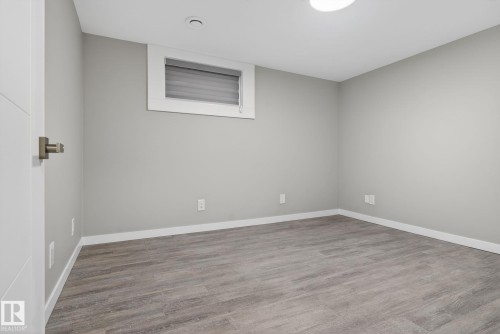 Spacious room featuring wood-finish flooring, light gray walls, and white trim - 13332 106 Street, Edmonton, AB - Indoor Photo Showing Other Room