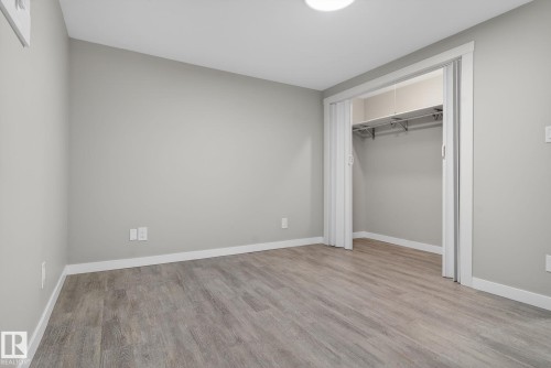Room featuring wood-finish flooring, light gray walls, white baseboards, and a bi-fold closet with an integrated hanging rod and shelving - 13332 106 Street, Edmonton, AB - Indoor Photo Showing Other Room