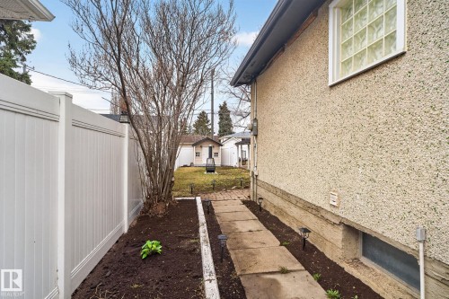 Stucco exterior featuring a glass block window and a concrete paver walkway - 13332 106 Street, Edmonton, AB - Outdoor With Exterior