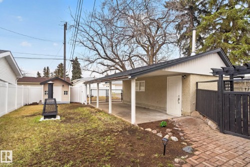 Expansive backyard featuring a covered patio, a detached storage shed, a brick pathway, and white privacy fencing - 13332 106 Street, Edmonton, AB - Outdoor