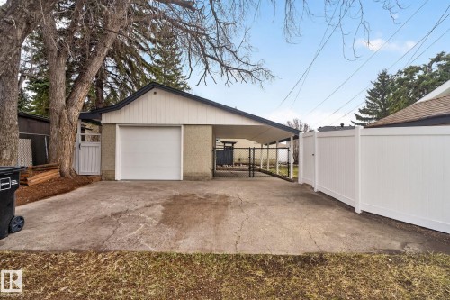 Detached garage with white overhead door, carport, and concrete driveway - 13332 106 Street, Edmonton, AB - Outdoor