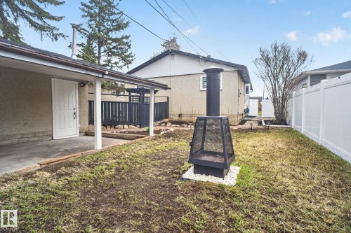 Fenced backyard featuring a freestanding outdoor fireplace set on a white gravel base - 13332 106 Street, Edmonton, AB - Outdoor