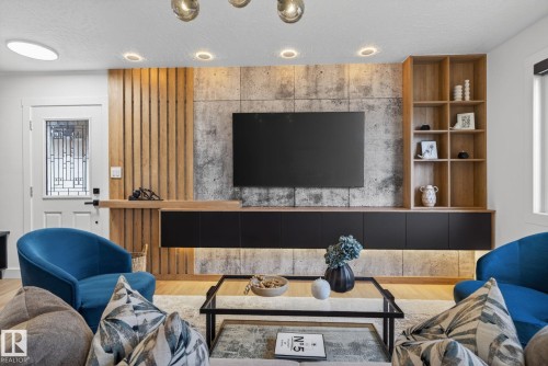 Integrated entertainment wall featuring a mounted television, a built-in shelving unit, and a floating console with under-cabinet lighting - 13332 106 Street, Edmonton, AB - Indoor Photo Showing Other Room