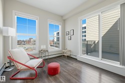 Spacious room with large windows, wood-finish flooring, and a sliding glass door leading to a private balcony with metal railings - 