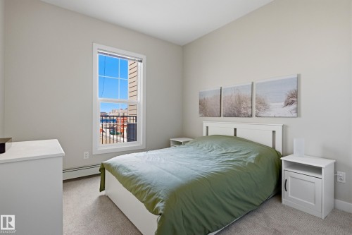Bright bedroom featuring a large window with white trim, light gray walls, and carpet flooring - 403 10418 81 Avenue, Edmonton, AB - Indoor Photo Showing Bedroom