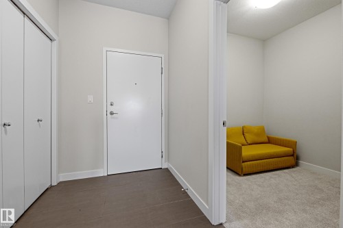 Entryway featuring a solid core door with chrome hardware, dual white bi-fold closet doors, and large format tile flooring - 403 10418 81 Avenue, Edmonton, AB - Indoor Photo Showing Other Room