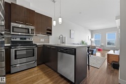 Kitchen featuring stainless steel appliances, dark wood-finish cabinetry, light countertops, and wood-finish flooring - 