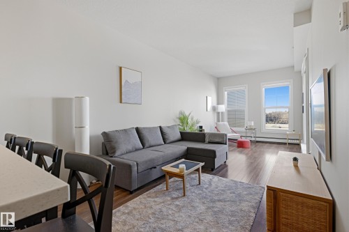 Open-concept living area featuring wood-finish flooring, white walls, and bright natural light from multiple windows - 403 10418 81 Avenue, Edmonton, AB - Indoor Photo Showing Living Room