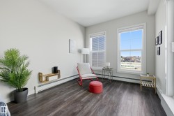 Bright room featuring two large windows, wood-finish flooring, white baseboards, and a built-in wall shelf - 