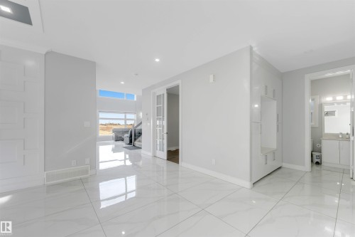 Spacious room featuring large format white tile flooring with a polished finish, light gray painted walls, and ample natural light from extensive window placements - 3736 1 Avenue Sw, Edmonton, AB - Indoor Photo Showing Other Room