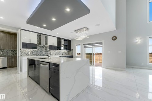 Contemporary kitchen featuring a large waterfall-edge island, high-gloss cabinetry, mosaic tile backsplash, and stainless steel appliances - 3736 1 Avenue Sw, Edmonton, AB - Indoor Photo Showing Kitchen With Upgraded Kitchen