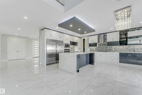 Modern kitchen featuring a waterfall island with a rectangular sink, stainless steel appliances, white and gray cabinetry, a mosaic tile backsplash, and large format tile flooring - 3736 1 Avenue Sw, Edmonton, AB - Indoor Photo Showing Kitchen With Upgraded Kitchen
