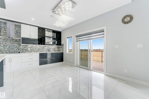 Sleek kitchen with glossy white and dark cabinetry, mosaic tile backsplash, stainless steel range hood, and polished tile flooring - 3736 1 Avenue Sw, Edmonton, AB - Indoor Photo Showing Kitchen