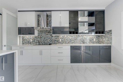 Modern kitchen featuring two-tone cabinetry with white and gray high-gloss finishes, a mosaic tile backsplash, and light-toned countertops - 3736 1 Avenue Sw, Edmonton, AB - Indoor Photo Showing Kitchen