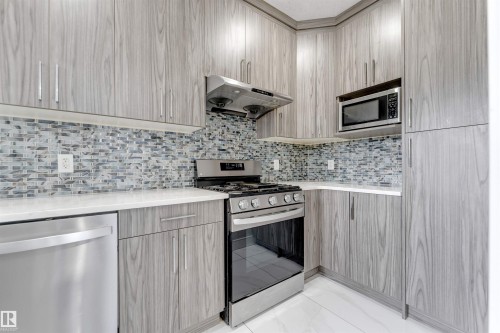 Kitchen featuring stainless steel appliances, light wood-finish cabinetry, white countertops, and a patterned tile backsplash - 3736 1 Avenue Sw, Edmonton, AB - Indoor Photo Showing Kitchen With Upgraded Kitchen