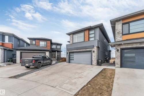 Contemporary exterior featuring a flat roofline, dark grey stucco, stone veneer accents, and light wood-tone siding - 3736 1 Avenue Sw, Edmonton, AB - Outdoor With Facade