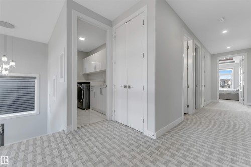 Upper-level hallway with patterned carpeting, featuring a laundry room with white cabinetry and a built-in sink - 3736 1 Avenue Sw, Edmonton, AB - Indoor Photo Showing Other Room