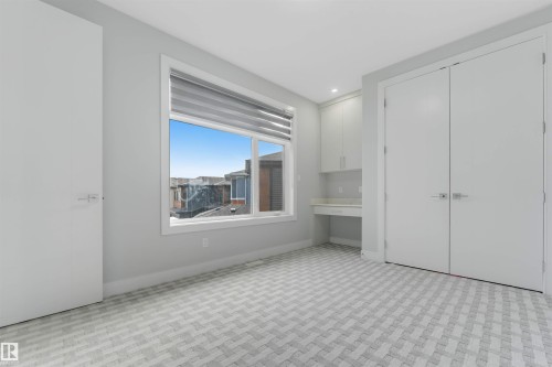 Bright room featuring a large window, light gray walls, and patterned carpet flooring - 3736 1 Avenue Sw, Edmonton, AB - Indoor Photo Showing Other Room