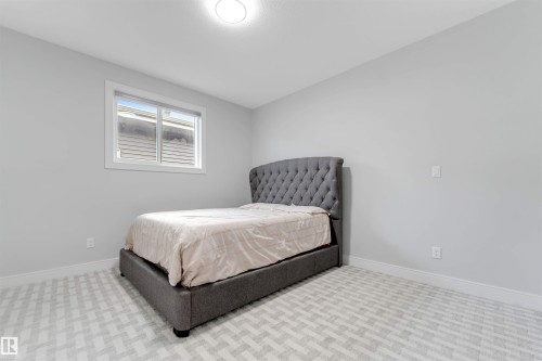 Bedroom featuring a large window, light gray walls, and geometric pattern carpet - 3736 1 Avenue Sw, Edmonton, AB - Indoor Photo Showing Bedroom