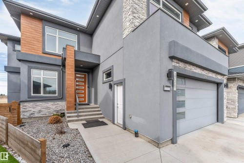 Contemporary exterior featuring a smooth stucco finish, natural wood-look paneling, and stacked stone accents - 3736 1 Avenue Sw, Edmonton, AB - Outdoor