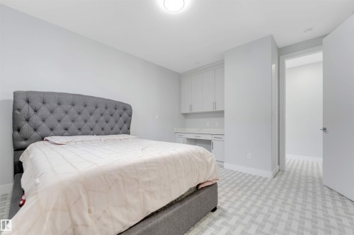Bedroom featuring a built-in desk with overhead cabinetry and a light-toned patterned carpet - 3736 1 Avenue Sw, Edmonton, AB - Indoor Photo Showing Bedroom