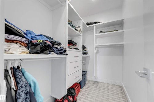 Custom closet system featuring white built-in shelving, hanging rods, and integrated drawers with contemporary pulls - 3736 1 Avenue Sw, Edmonton, AB - Indoor With Storage