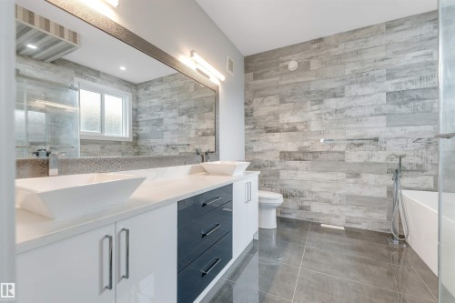 Bathroom featuring a dual vanity with vessel sinks, white countertop, and dark cabinetry accents - 3736 1 Avenue Sw, Edmonton, AB - Indoor Photo Showing Bathroom