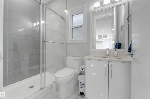 Bathroom with a glass-enclosed shower featuring large format grey wall tiles - 3736 1 Avenue Sw, Edmonton, AB - Indoor Photo Showing Bathroom