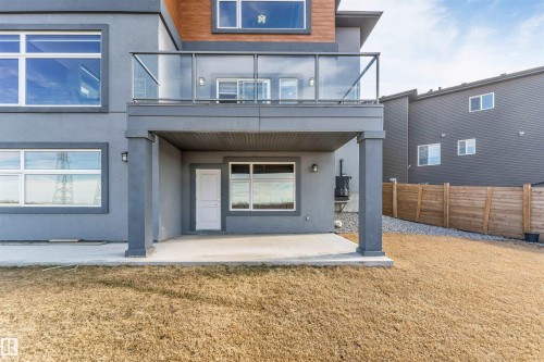 Rear exterior featuring a ground-level patio and an upper-level balcony with glass railings - 3736 1 Avenue Sw, Edmonton, AB - Outdoor With Exterior