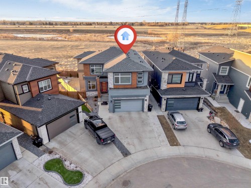 Modern multi-story residence featuring a dark gray roof, stone facade accents, an attached two-car garage, and a concrete driveway - 3736 1 Avenue Sw, Edmonton, AB - Outdoor