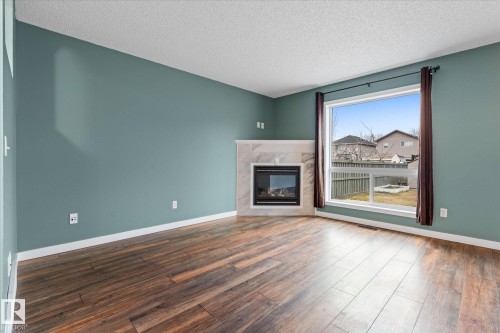 Corner gas fireplace with a light-colored tile surround and hearth - 5407 204 Street, Edmonton, AB - Indoor Photo Showing Living Room With Fireplace