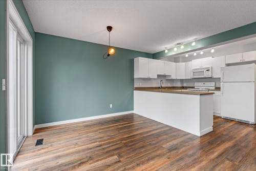 Open-concept living space featuring wood-finish flooring and a contemporary pendant light fixture - 5407 204 Street, Edmonton, AB - Indoor Photo Showing Kitchen