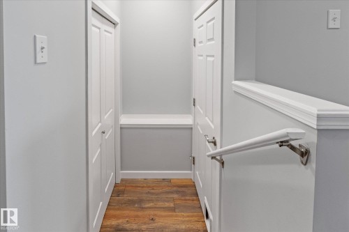 Hallway featuring wood-finish flooring, light gray wall paint, and white trim molding - 5407 204 Street, Edmonton, AB - Indoor Photo Showing Other Room