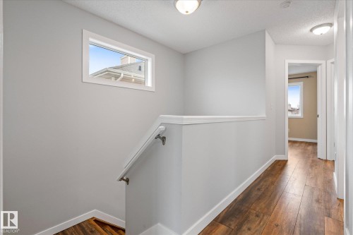 Upper-level hallway with wood-finish flooring, light gray wall paint, and white trim - 5407 204 Street, Edmonton, AB - Indoor Photo Showing Other Room
