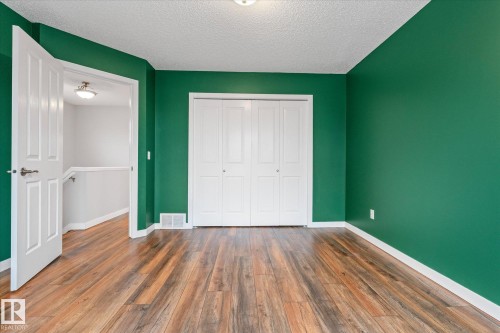 Room featuring vibrant green walls, wood-finish flooring, white baseboards, and a white bi-fold closet - 5407 204 Street, Edmonton, AB - Indoor Photo Showing Other Room