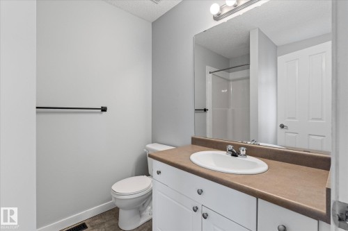 Bathroom featuring a white vanity with an integrated sink, a brown countertop, and a large mirror - 5407 204 Street, Edmonton, AB - Indoor Photo Showing Bathroom