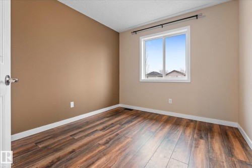Room featuring wood-finish flooring, neutral wall tones, white trim, and a prominent window with a white frame - 5407 204 Street, Edmonton, AB - Indoor Photo Showing Other Room