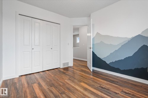 Wood-finish flooring throughout, complemented by a decorative accent wall with a mountain mural design - 5407 204 Street, Edmonton, AB - Indoor