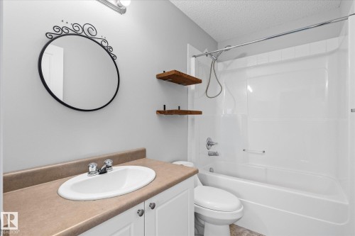 Bathroom featuring a white vanity with a tan countertop, an oval undermount sink, and a chrome faucet - 5407 204 Street, Edmonton, AB - Indoor Photo Showing Bathroom