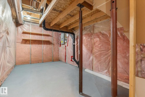 Unfinished basement featuring exposed wood framing, insulation, a painted concrete floor, and built-in shelving - 5407 204 Street, Edmonton, AB - Indoor Photo Showing Basement