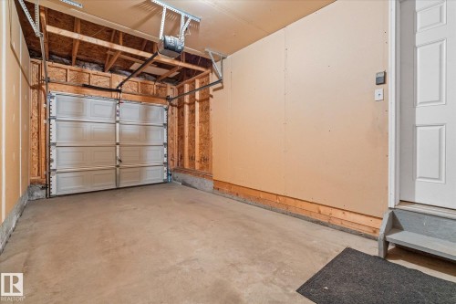 Attached garage featuring a concrete floor, automatic garage door opener, and a panel-style interior door - 5407 204 Street, Edmonton, AB - Indoor Photo Showing Garage