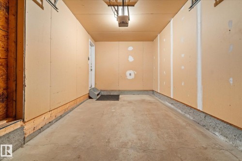 Single-car garage with concrete flooring, finished walls, overhead lighting, and an interior access door - 5407 204 Street, Edmonton, AB - Indoor Photo Showing Other Room