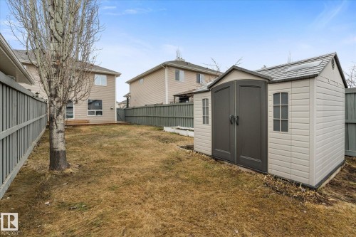 Expansive backyard featuring a built-in storage shed with double doors and side windows, a wooden deck, and a full perimeter fence - 5407 204 Street, Edmonton, AB - Outdoor With Exterior