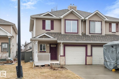 Multi-level townhouse exterior featuring beige siding, white trim, and a dark purple entry door - 5407 204 Street, Edmonton, AB - Outdoor With Facade