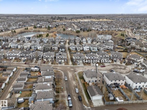 Aerial perspective showcasing a residential area with detached properties, a visible street network, and a prominent water feature - 5407 204 Street, Edmonton, AB - Outdoor With View