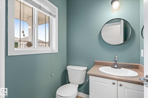 Bathroom vanity with a circular mirror, single basin sink, and chrome faucet - 5407 204 Street, Edmonton, AB - Indoor Photo Showing Bathroom