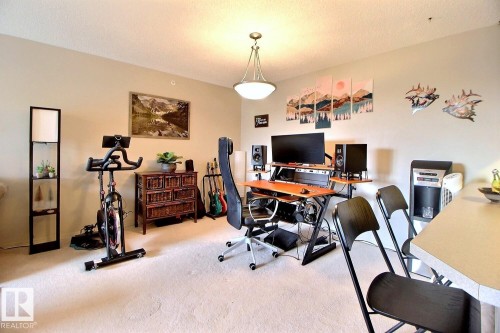 Open concept living area with carpeting, light beige wall color, and a ceiling-mounted light fixture - 413 279 Suder Greens Drive, Edmonton, AB - Indoor